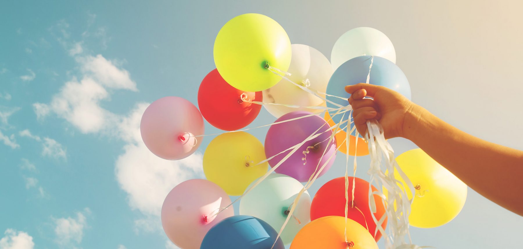 alt=Luftballons werden in Himmel gehalten